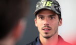 Close-up of a young man wearing a camouflage cap with the number 96, speaking to someone off-screen.