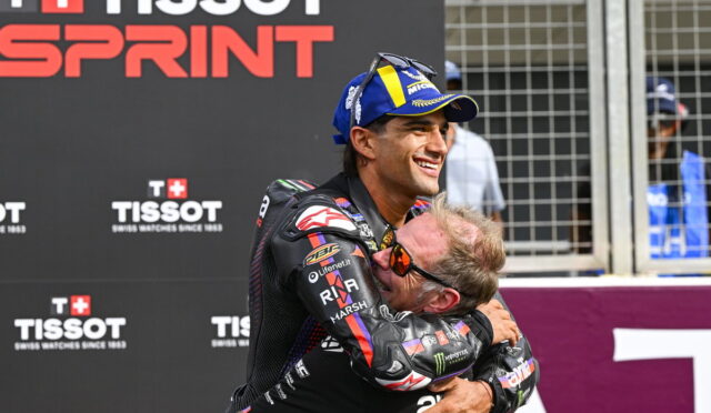 Two motorcyclists embrace in a congratulatory hug at a Tissot Sprint event, with branding in the background.