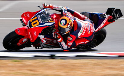 Motorcycle racer on a red Honda bike, number 10, leaning into a corner on a race track.
