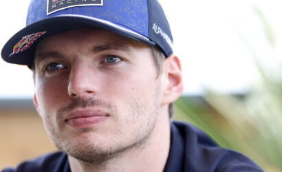 Close-up portrait of a man wearing a blue Oracle Red Bull Racing cap, looking off to the side.