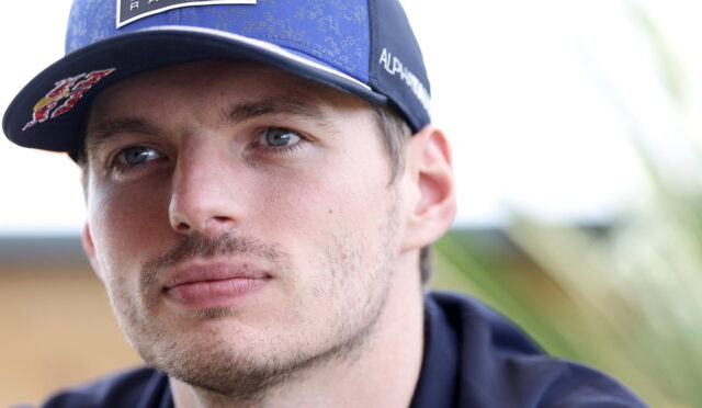 Close-up portrait of a man wearing a blue Oracle Red Bull Racing cap, looking off to the side.