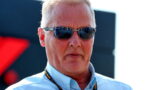 Man wearing a light blue shirt and dark sunglasses at an outdoor event, with a black lanyard around his neck.