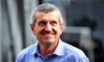 Smiling man in a light blue button-down shirt outdoors, looking to the side.