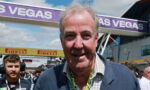 Older man in a blue blazer at a Las Vegas racing event, smiling, with Pirelli banners in the backgroundpo