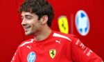 Man in a red Ferrari polo shirt smiling, with sponsor logos visible on the chest and sleeves.