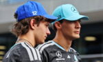 Two young men in Mercedes racing team jerseys stand side by side, wearing blue caps (one with 12, the other with 63) and sponsor logos on their shirts.