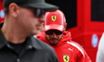 Man in a red Ferrari cap and hoodie with the crest, wearing sunglasses and looking downward.