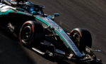 Mercedes-AMG Petronas Formula 1 car speeds around a corner on a race track, teal-silver livery and sponsor decals visible on the body.