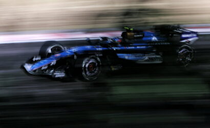 Blurred blue Formula 1 car speeding along track, motion blur conveying high speed and race action.
