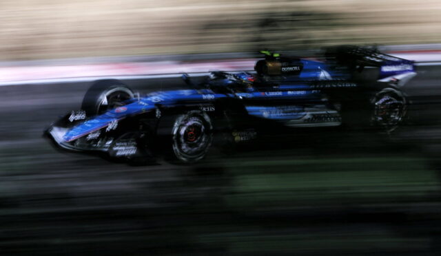 Blurred blue Formula 1 car speeding along track, motion blur conveying high speed and race action.