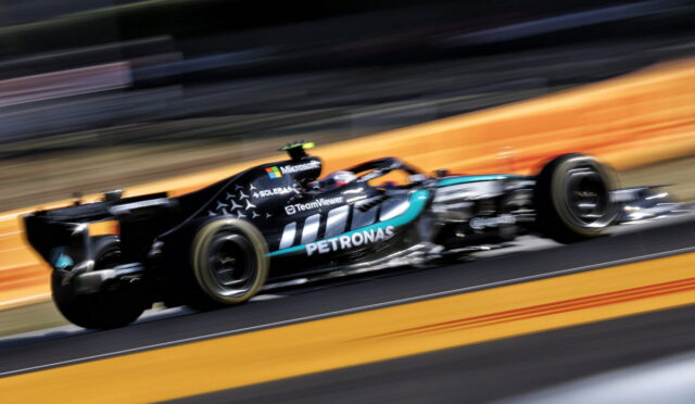 Mercedes-AMG Petronas Formula 1 car speeding on track with motion blur backdrop, sponsor logos visible like Petronas and Microsoft