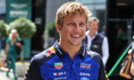 Smiling man in a Blue Red Bull Racing polo shirt with sponsor logos, standing outdoors at a race event (portrait).