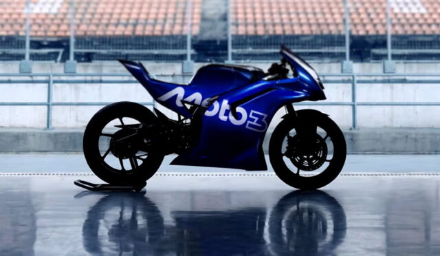 Blue Moto3 racing motorcycle parked on a glossy surface with empty stadium seating in the background